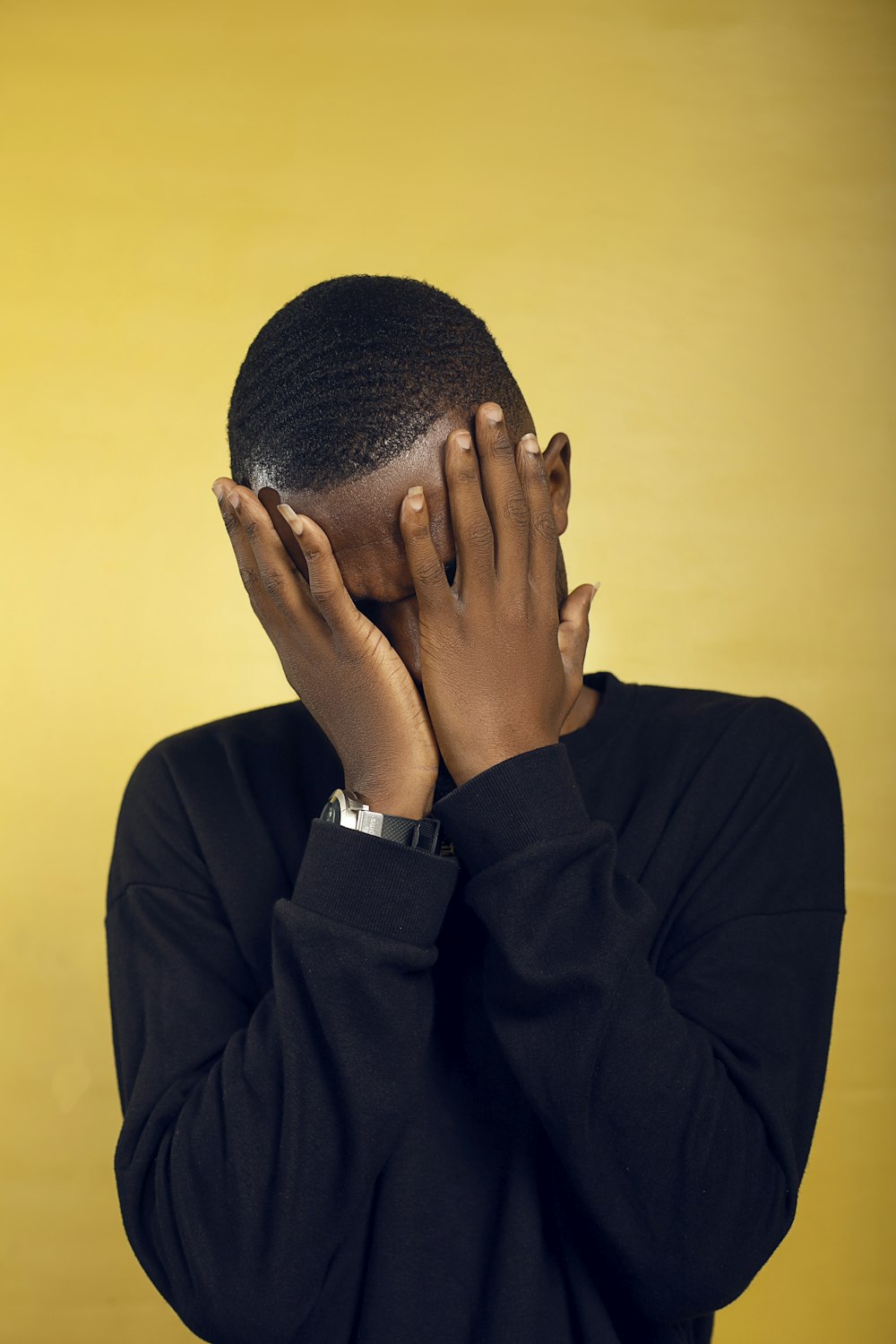 a man covering his face with his hands