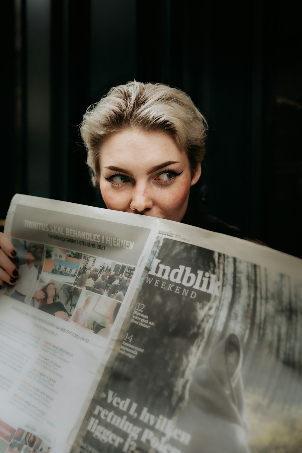 a woman reading a newspaper with her face close to the camera