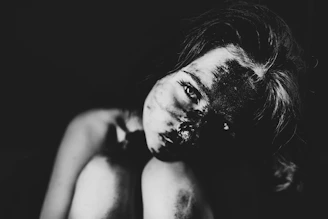 a black and white photo of a woman covered in mud