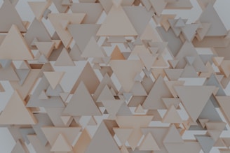 A pattern consisting of various overlapping and layered triangles in shades of beige and gray, creating a three-dimensional geometric effect.