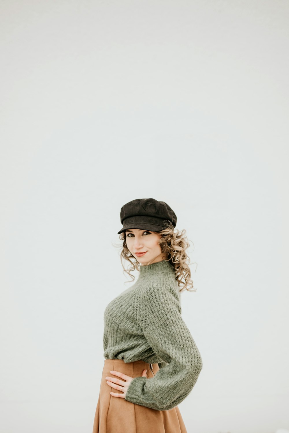 a woman in a green sweater and brown skirt