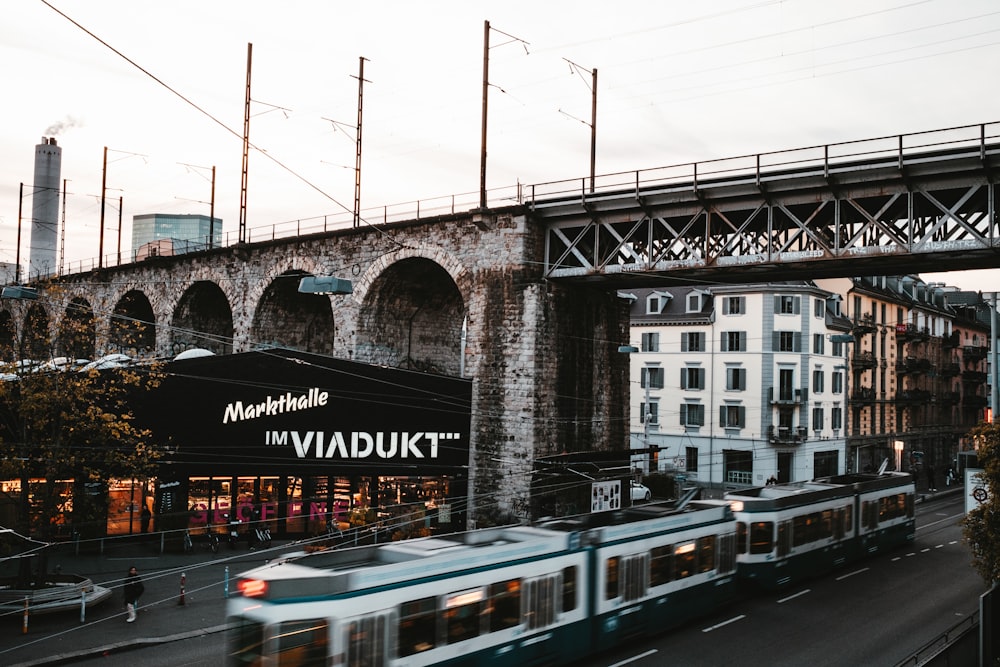 a train traveling under a bridge next to tall buildings