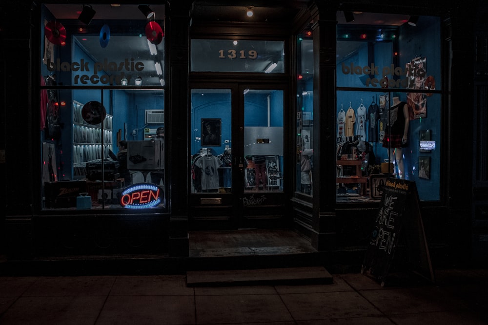 a store front at night with a neon sign in the window