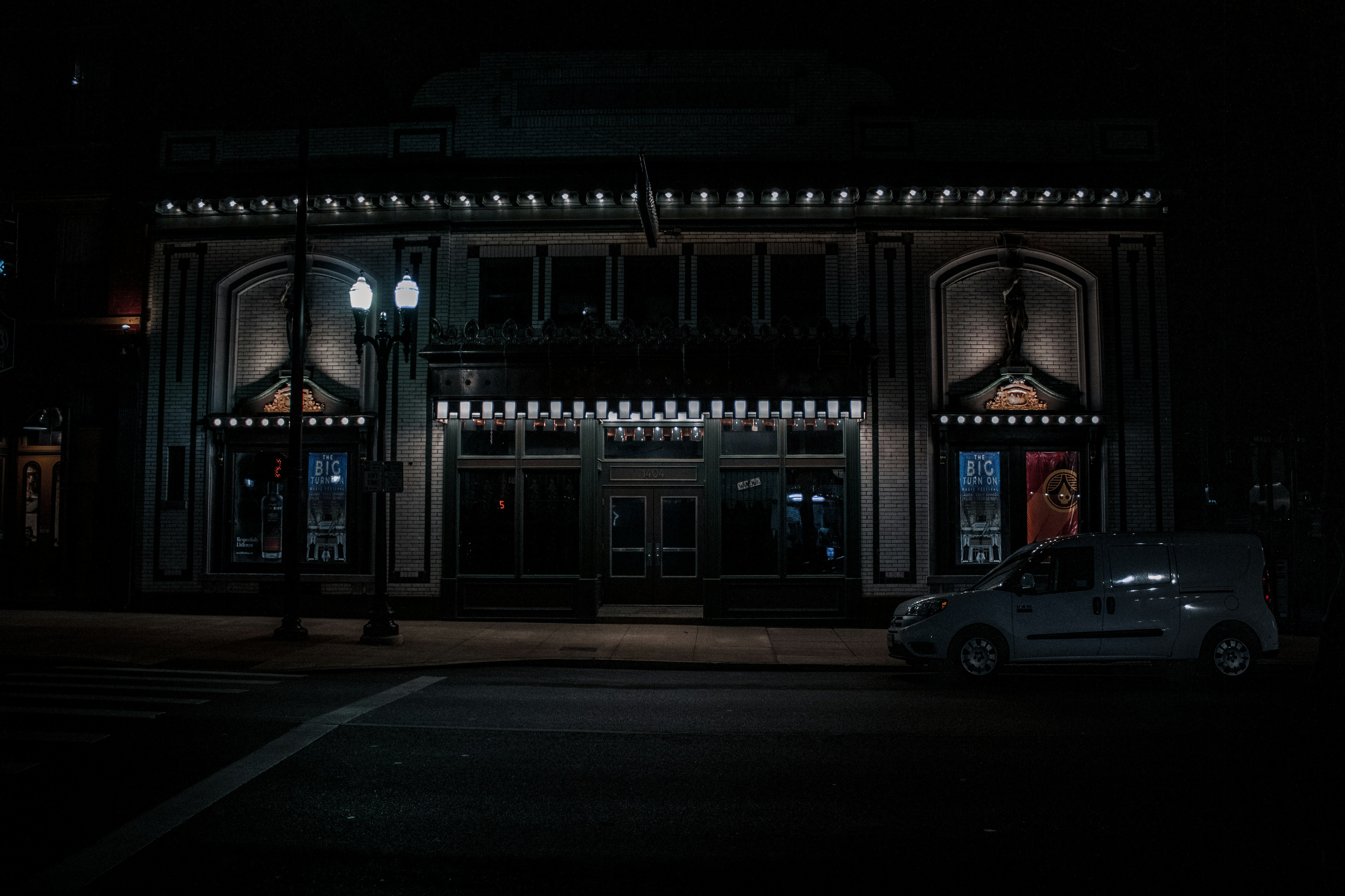 a car parked in front of a building at night, Woodward Theatre at night.