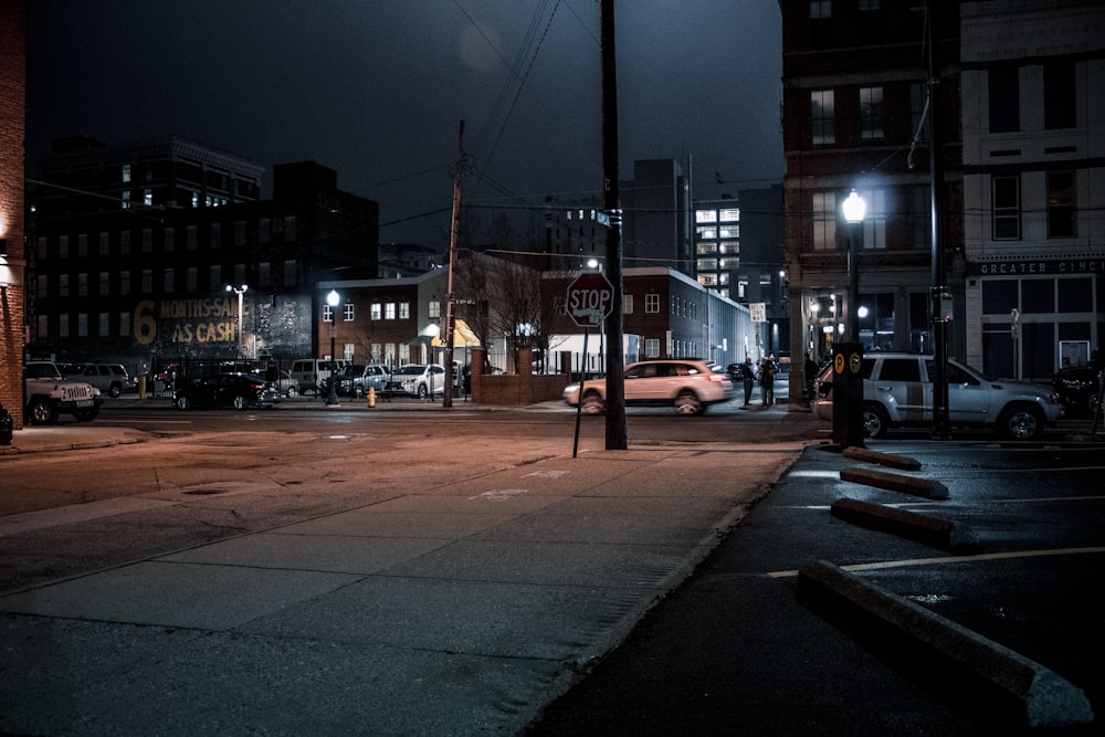 a city street at night with cars parked on the side of the road