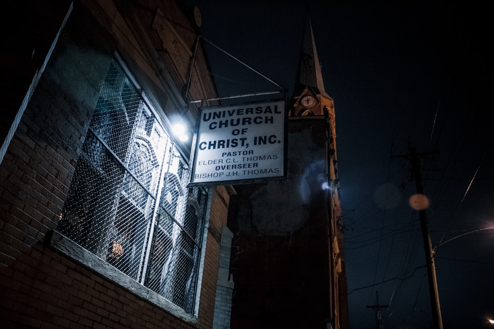 a church sign hanging from the side of a building