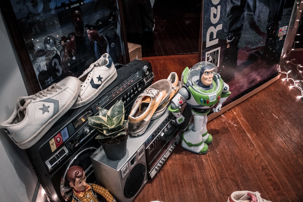 a pair of sneakers and a toy buzz lightyear sit on top of a stereo