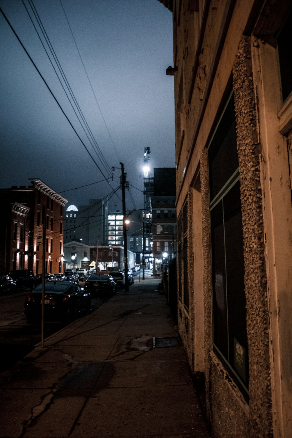 a city street at night with cars parked on the side of the street