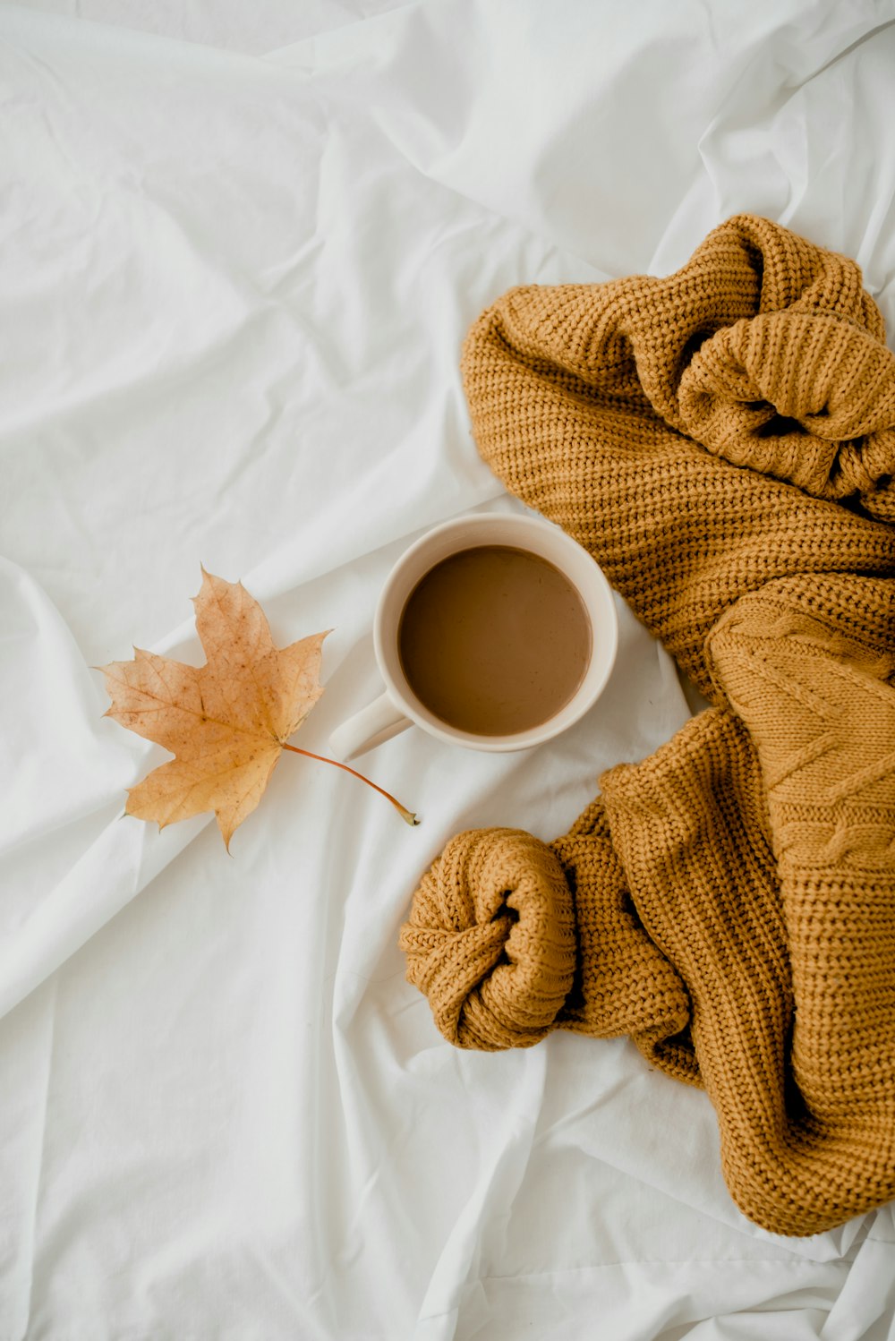 a cup of coffee and a blanket on a bed