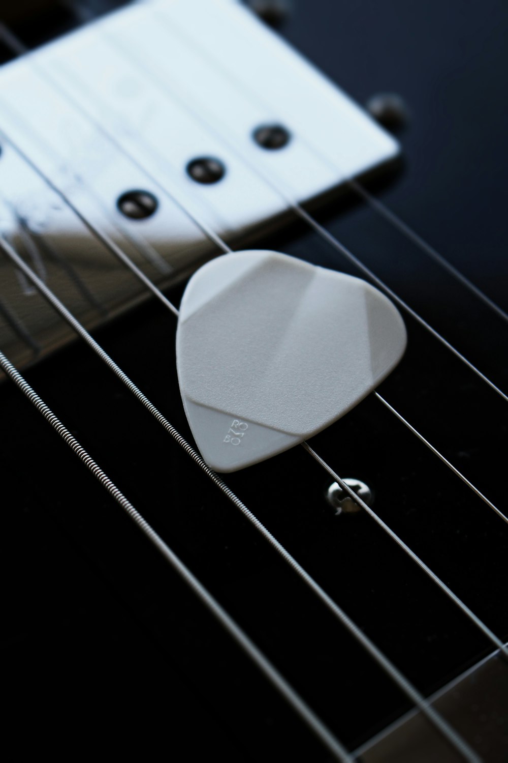 a white guitar pick sitting on top of a black guitar