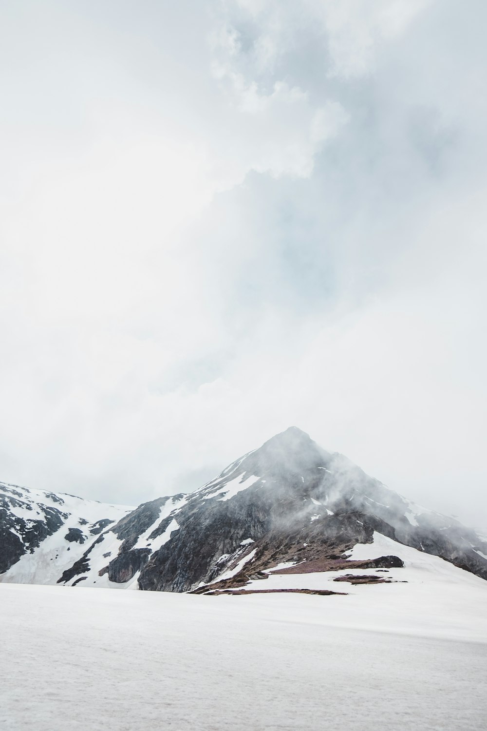 a mountain covered in snow with a cloudy sky