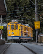 a yellow and blue trolley car traveling down a street