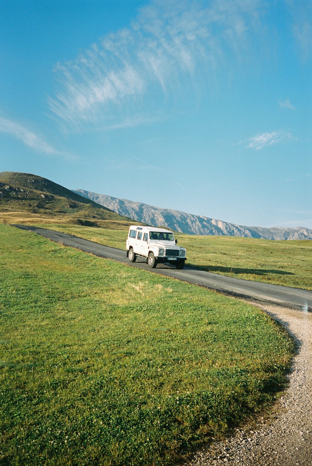 a van driving down a road in the middle of a field