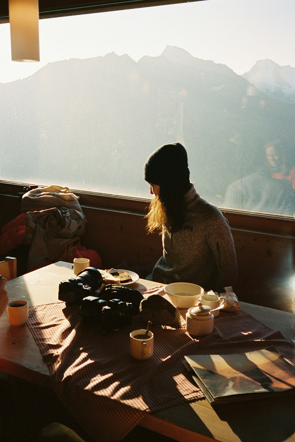 a woman sitting at a table in front of a window