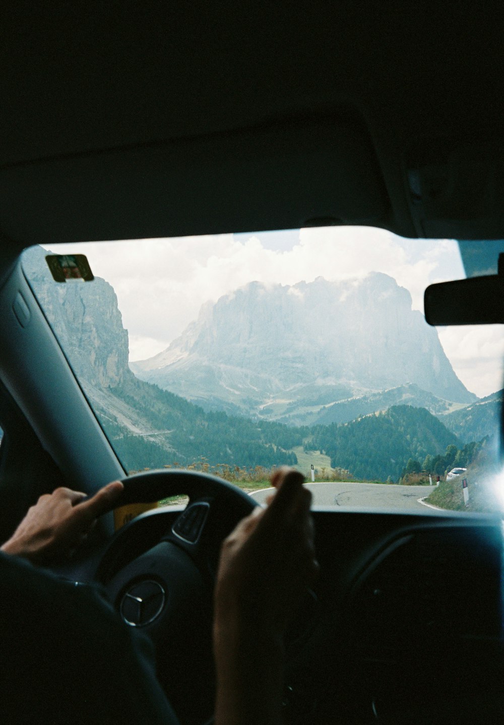 a person driving a car with mountains in the background