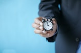 a man in a suit holding a small alarm clock