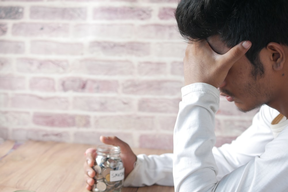 a man sitting at a table with a jar of coins