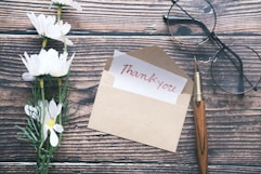 a thank you note sitting on top of a table next to a pair of glasses