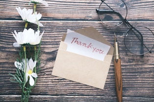 a thank you note sitting on top of a table next to a pair of glasses