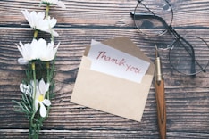 a thank you note sitting on top of a table next to a pair of glasses