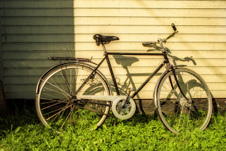 A cozy vintage bicycle leaning against a rustic wooden fence under soft morning light.