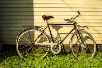 A vintage bicycle leaning against a rustic workshop wall, bathed in warm afternoon light.
