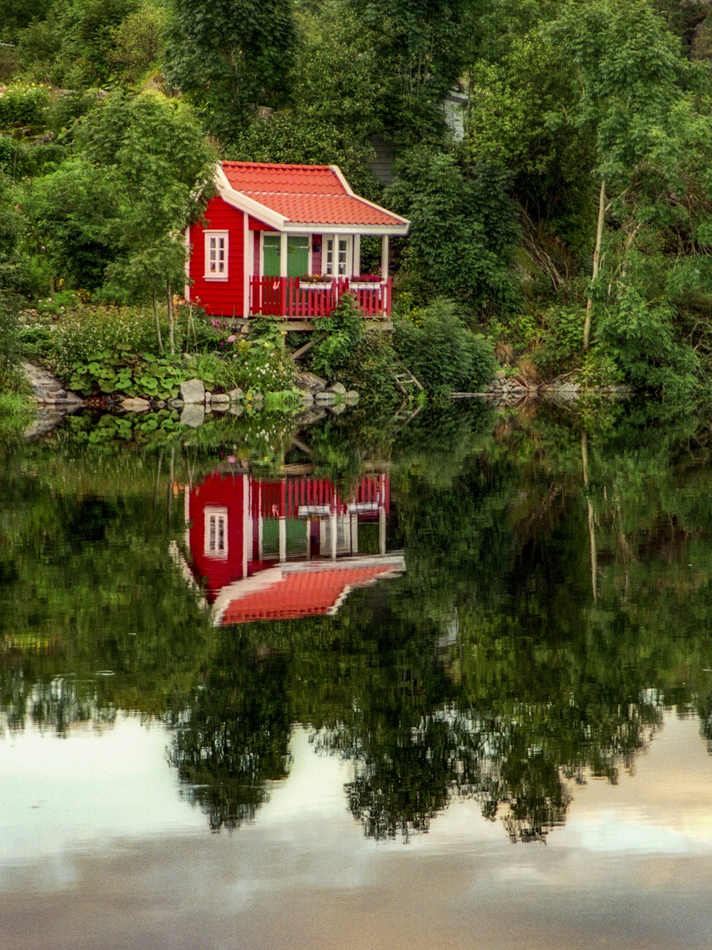 a small red house sitting on top of a lake
