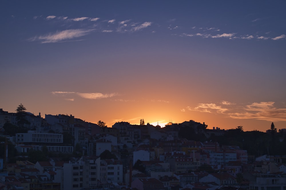 the sun is setting over a city with tall buildings