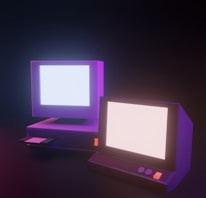 Close-up of vintage computer screens displaying colorful 3D graphics and pixel art.