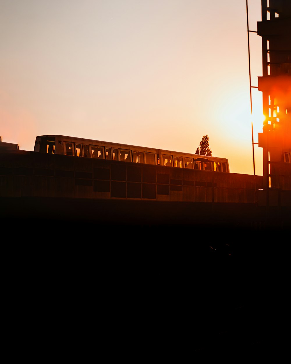 Un train passant devant un grand immeuble au coucher du soleil