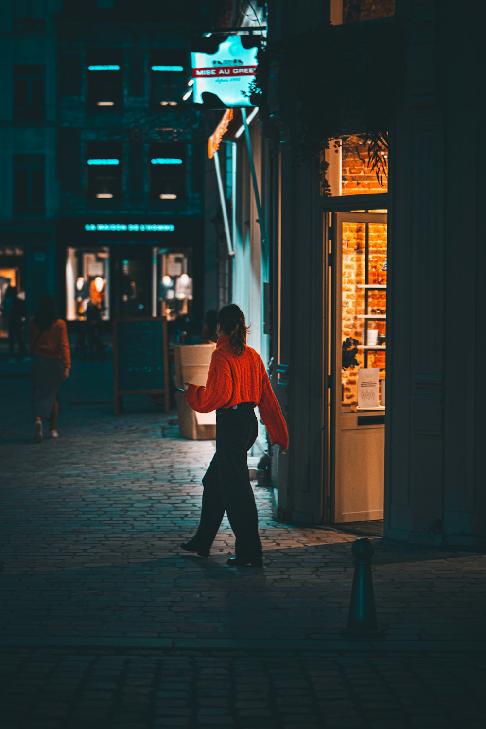 a woman walking down a street at night