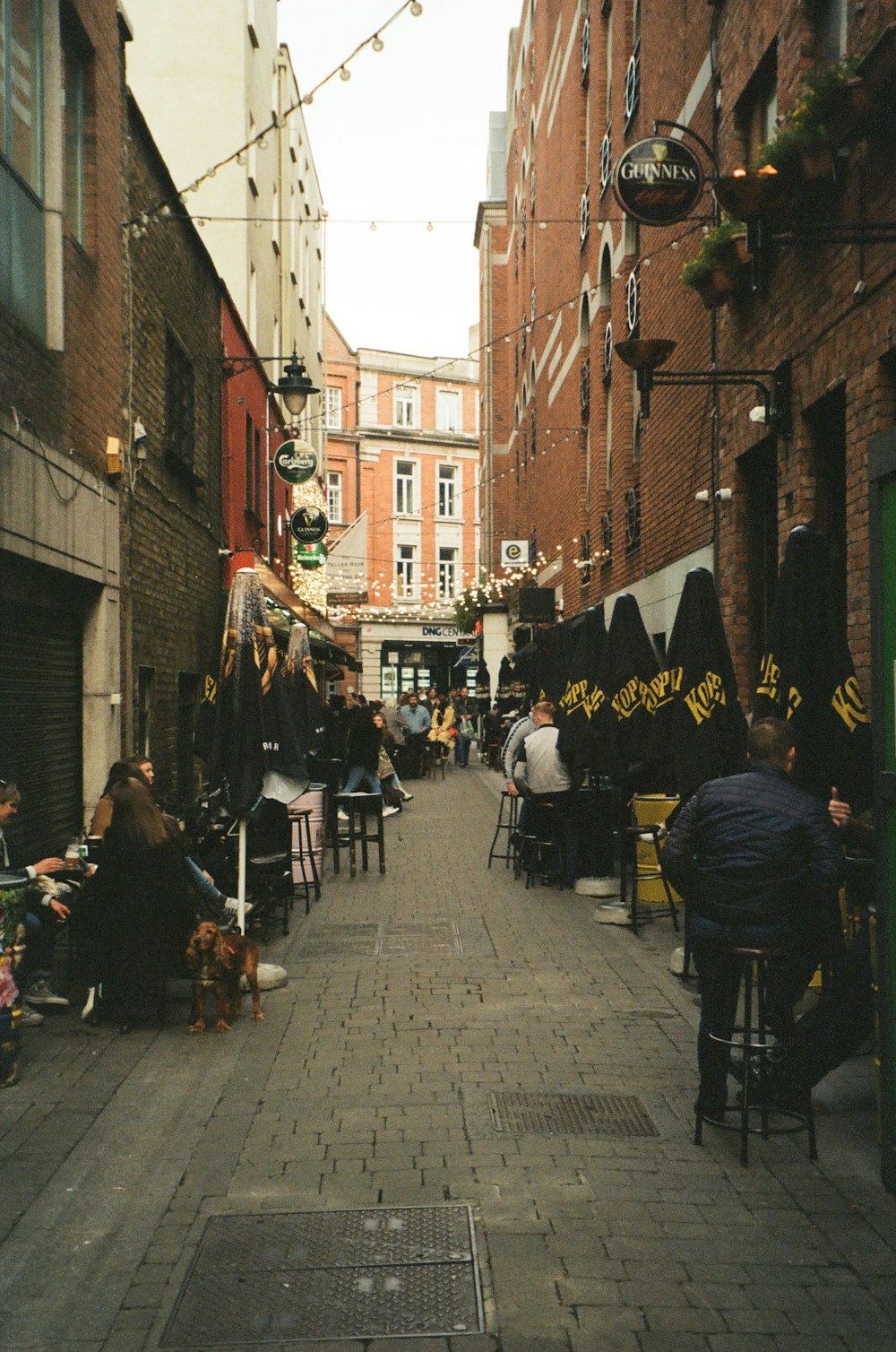 a group of people sitting at tables in an alley