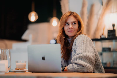 Softly lit photo of a young woman journaling at a cozy cafe table surrounded by blush pink and ivory decor.