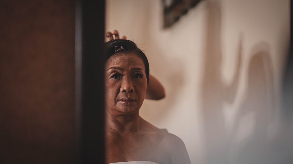 a woman in a white shirt is looking in a mirror