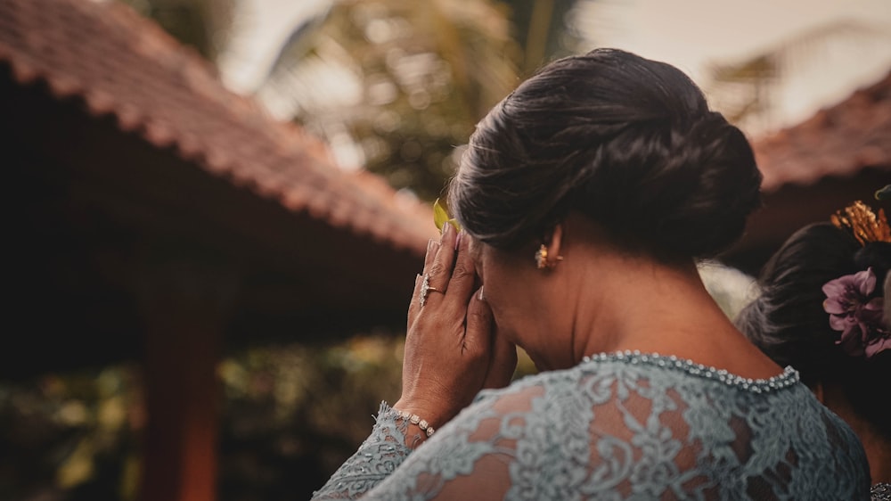 a woman standing in front of a building holding her hands to her face