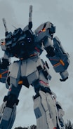 A large, humanoid robot with articulated joints and angular, armored plating stands prominently against a cloudy sky. The structure features intricate mechanical detailing and vibrant glowing lights accentuating its robust form.