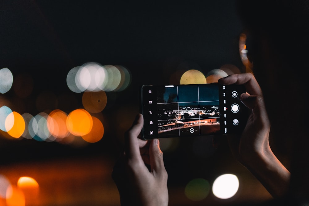 Una persona tomando una foto de una ciudad por la noche