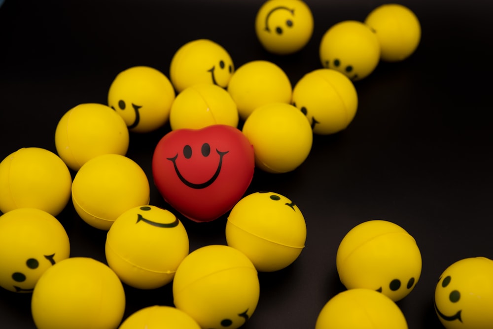 Un cœur rouge entouré de boules jaunes avec des visages souriants