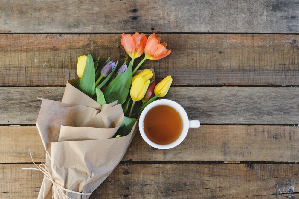 a bouquet of tulips next to a cup of tea