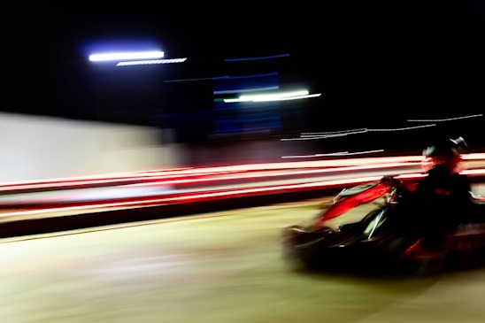 A dynamic shot of a racer speeding through the track with vibrant red and black karts in motion.