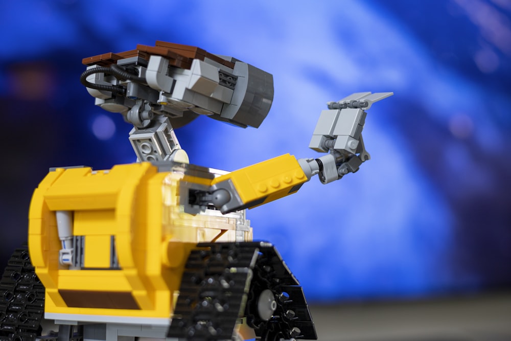 a yellow and black lego robot with a blue background