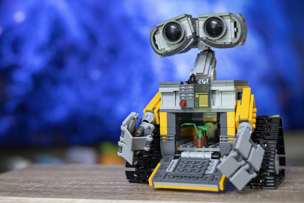 a lego robot with two large eyes and a plant