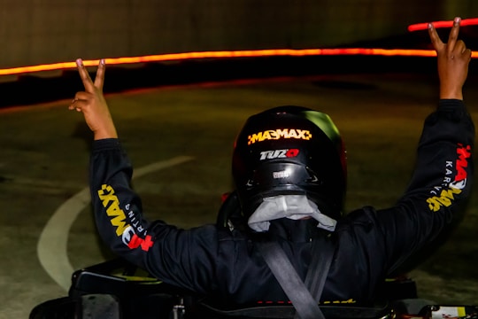 A dramatic shot of a Formula 1 driver celebrating on the podium with confetti falling.