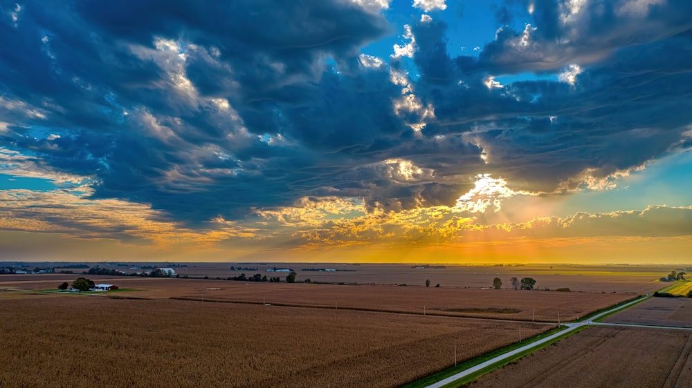 the sun is setting over a farm field