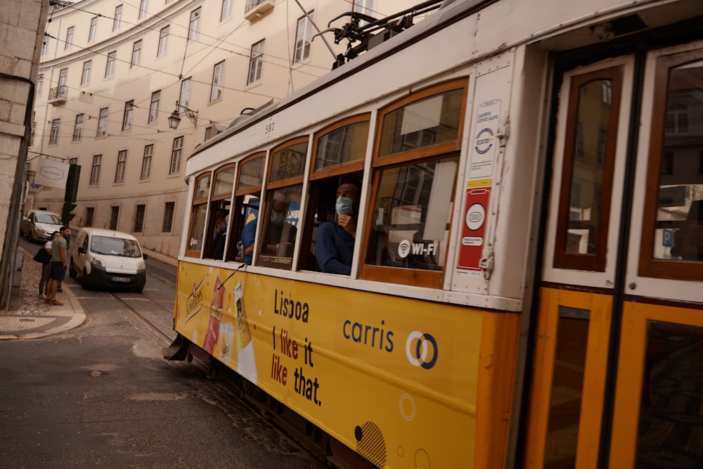 a yellow trolley car with people in it on a city street