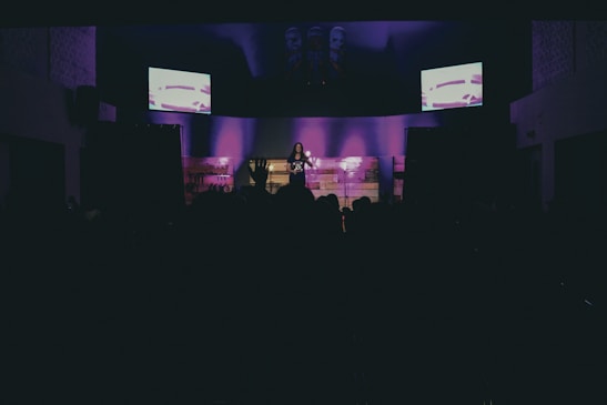 Photo of a dimly lit stage with a woman performing an intimate solo art piece.
