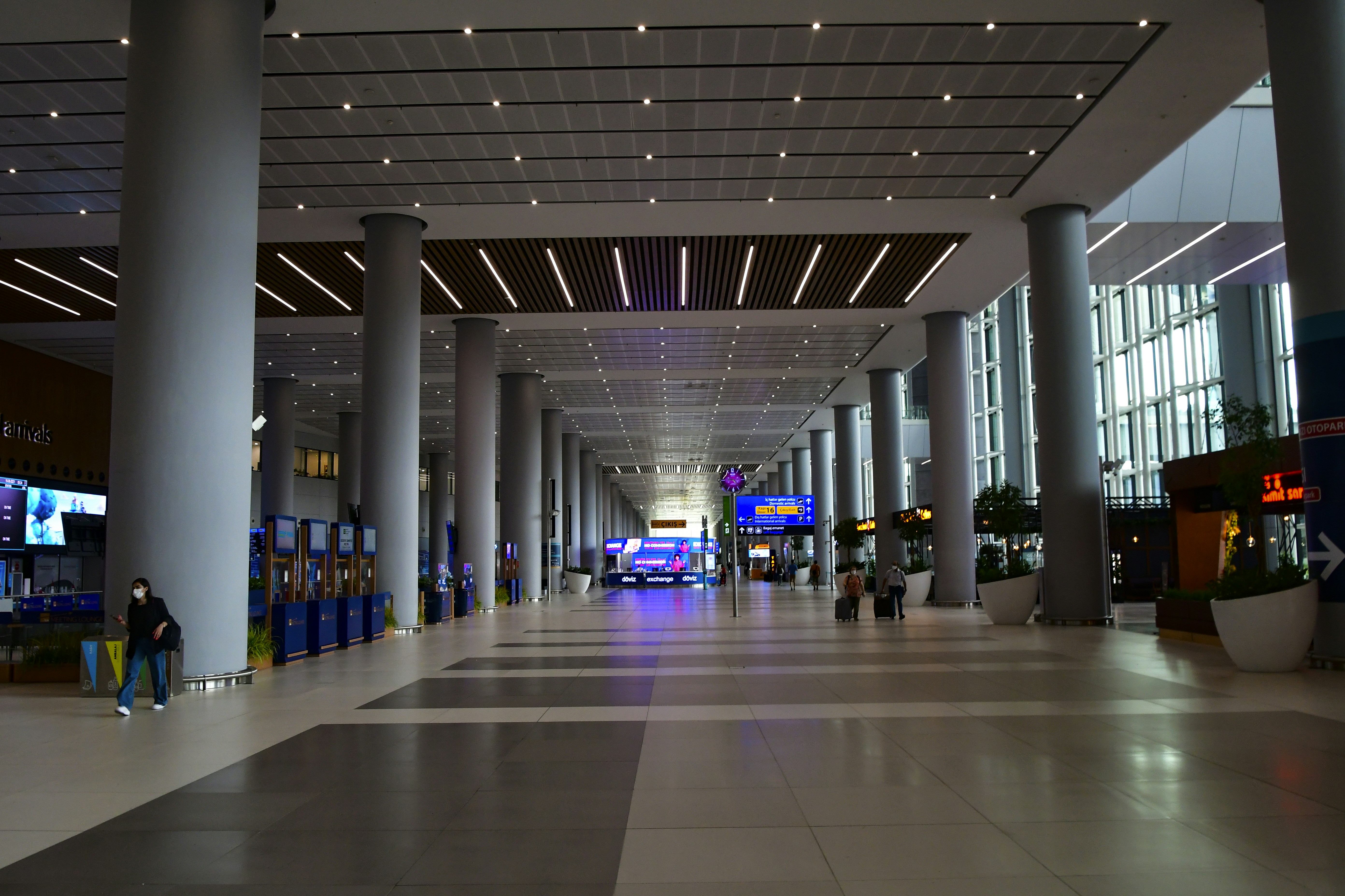 Modern airport terminal interior with bright lighting, business travelers with luggage, clean architectural lines