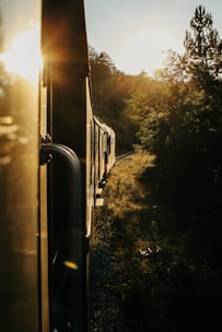 A luxurious heritage train winding through lush green valleys under a golden sunset.