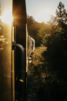 A scenic train winding through lush green mountains under a golden sunset.