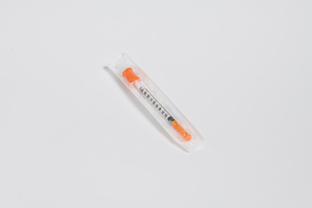 uma escova de dentes laranja e branca em uma superfície branca